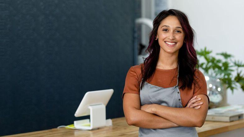 A female cashier stands with arms crossed